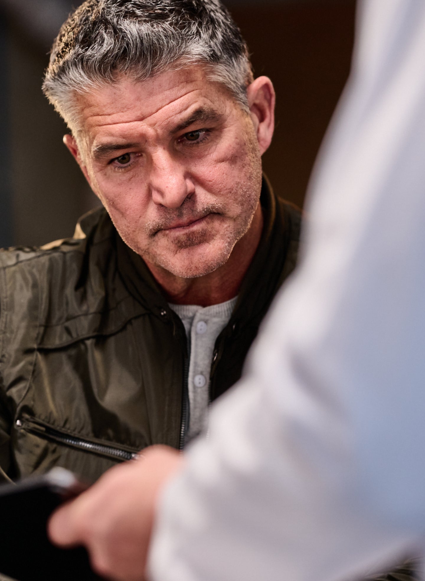 Middle-aged man attentively listening to a dental professional during a consultation about gingivitis and periodontitis at Aspen Dental.