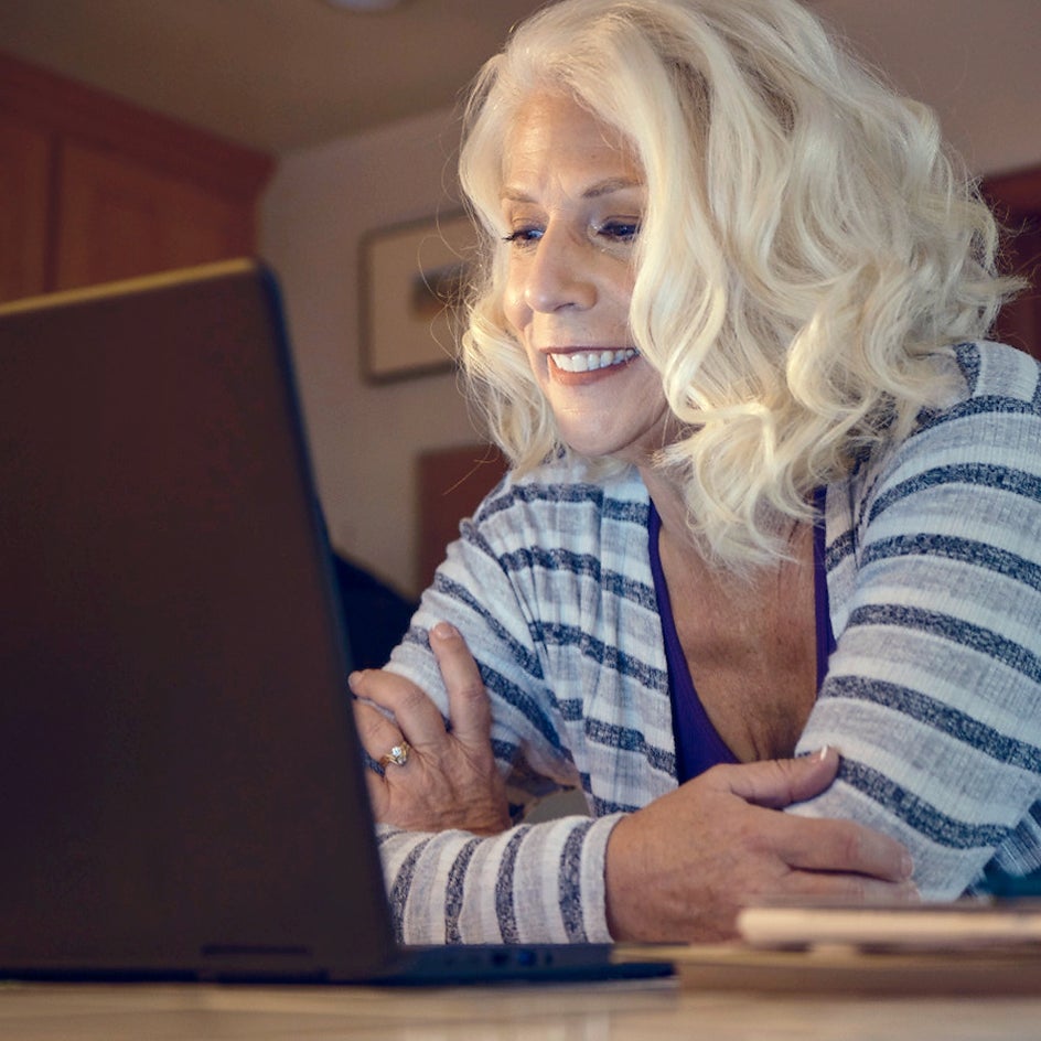 A woman with blonde hair researching dental implant options on her computer.