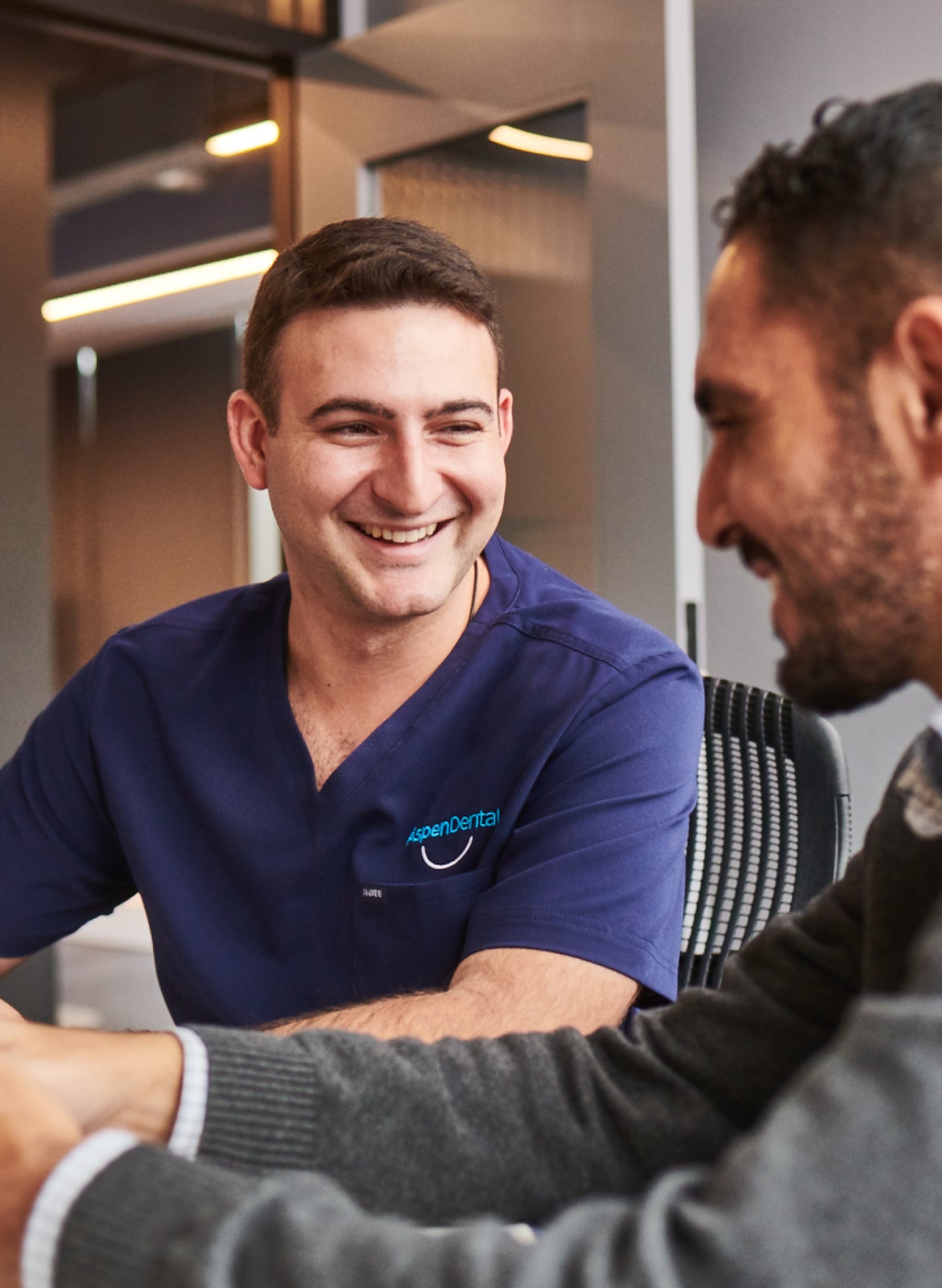Aspen Dental professional discussing molar dental implant costs with a patient in a comfortable office setting, emphasizing personalized care and cost transparency.