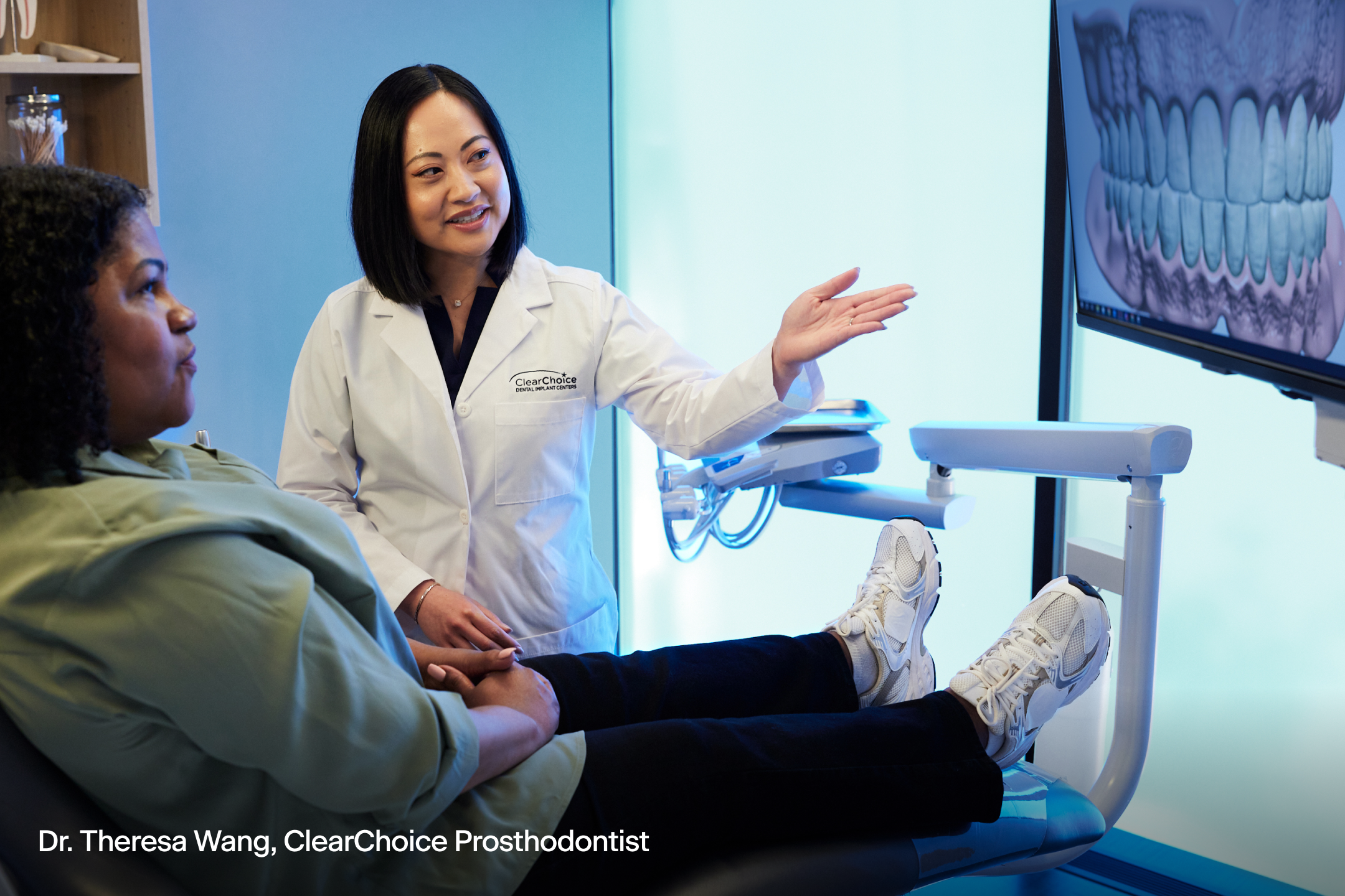 ClearChoice prosthodontist Dr. Theresa Wang explaining dental treatment options to a patient during consultation, with a dental scan on the screen.