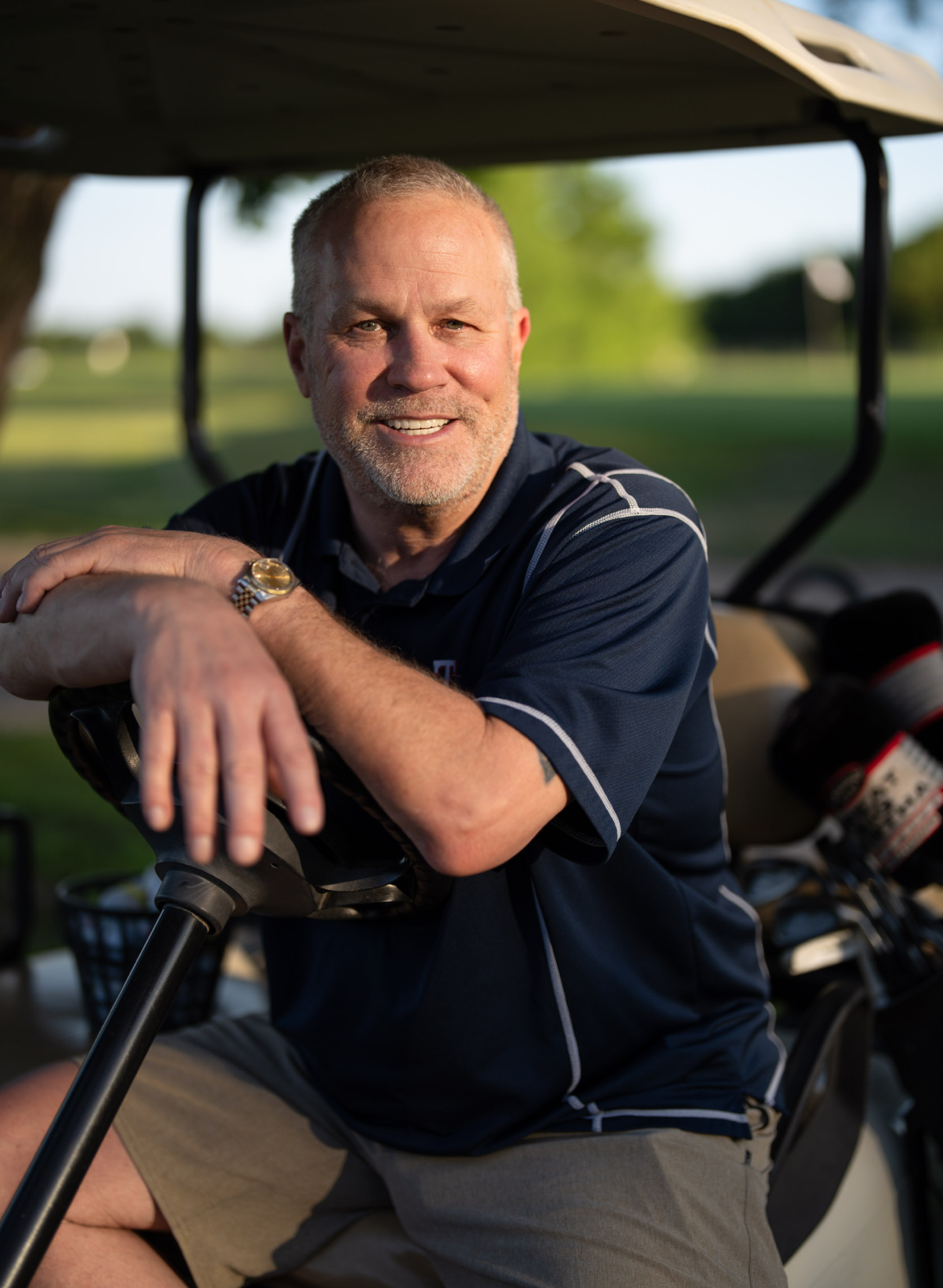 Smiling man sitting in a golf cart, representing the confidence and lifestyle benefits of permanent dental implants discussed in ClearChoice's guide to their longevity.