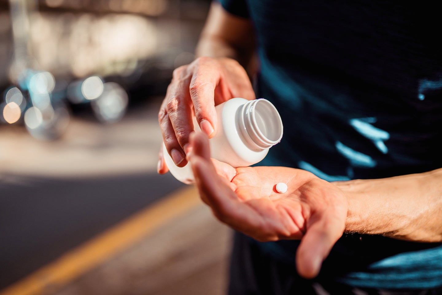 A close-up of a person’s hands pouring a pill from a bottle, preparing to take medication. The image suggests the use of antibiotics or pain relief for gum inflammation or dental infections. Aspen Dental provides expert care and treatment solutions for oral health issues.