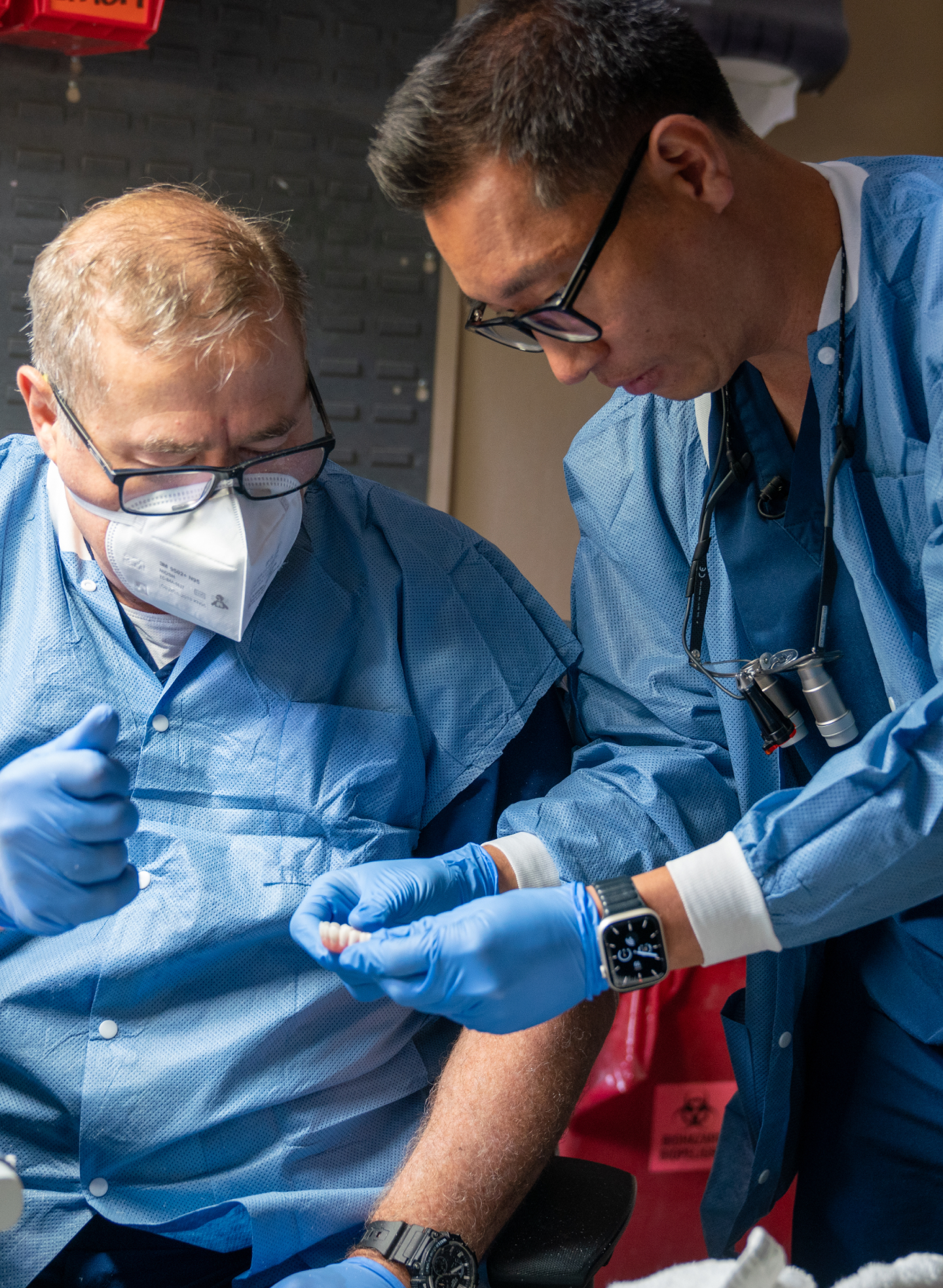 Two dental professionals at ClearChoice collaborating on a zygomatic dental implant procedure, both wearing blue surgical gowns and gloves for precision and safety.