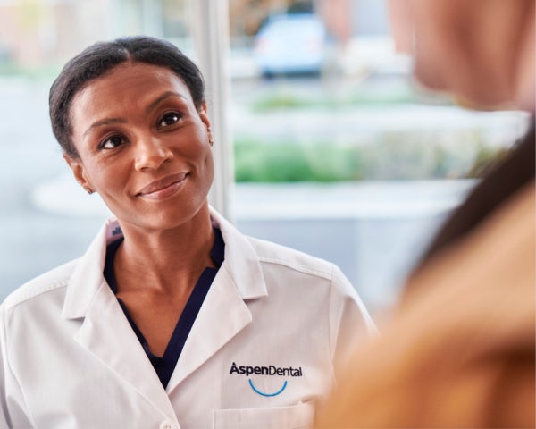  A dentist in an Aspen Dental uniform warmly engages with a patient during a consultation, reflecting personalized and approachable dental care.