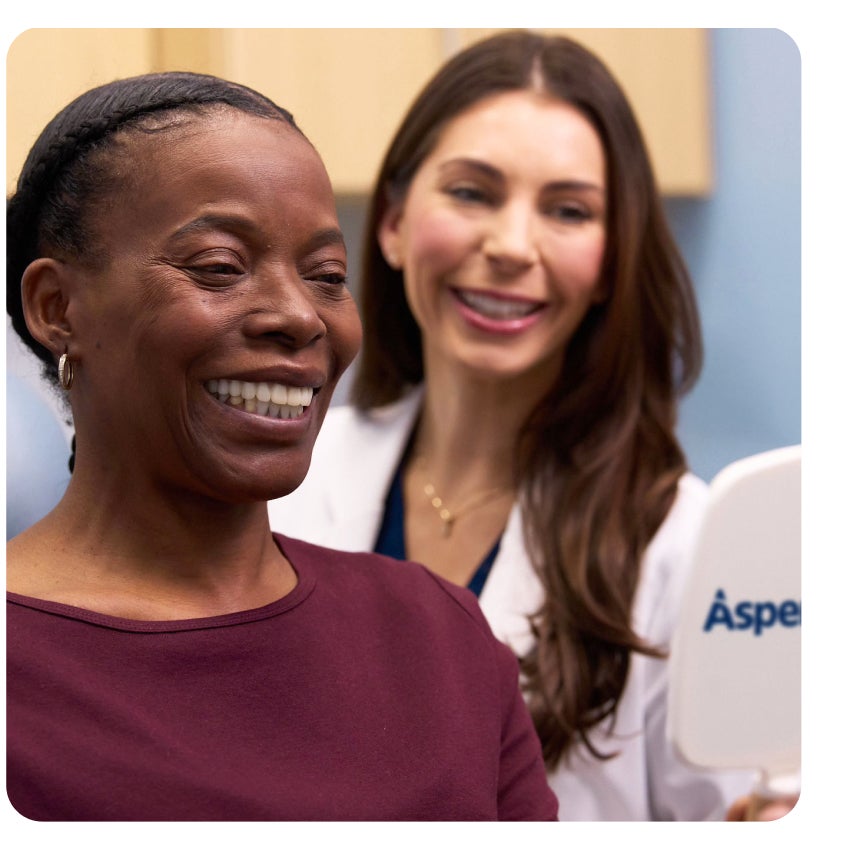 Aspen Dental cosmetic dentist showing a patient her beautiful smile results in a mirror after treatment