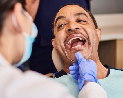 A man is laughing while a dentist examines his teeth