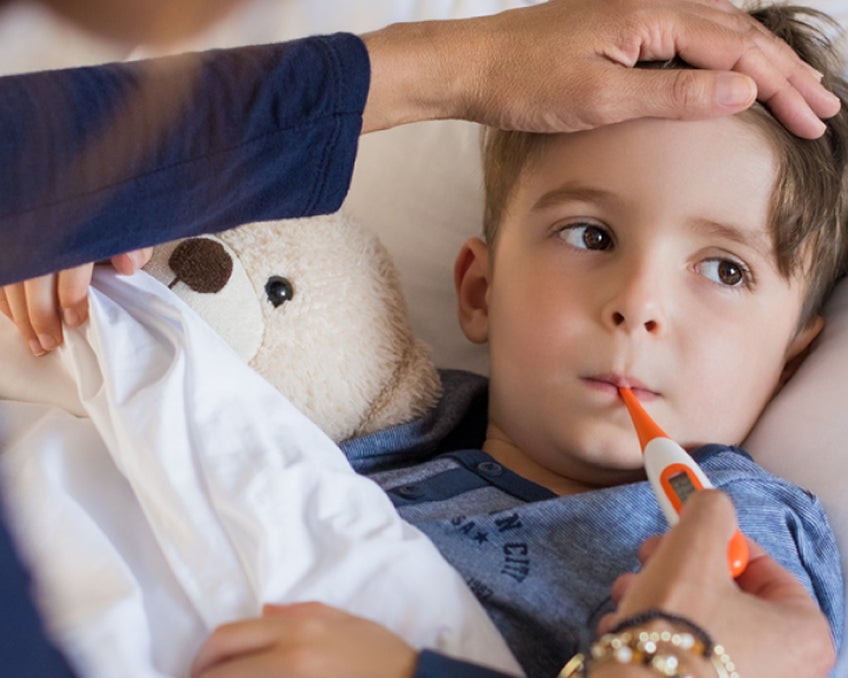 A close up photo of a child getting their temperature taken.