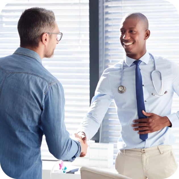 A medical provider shaking hands with a person in business attire.