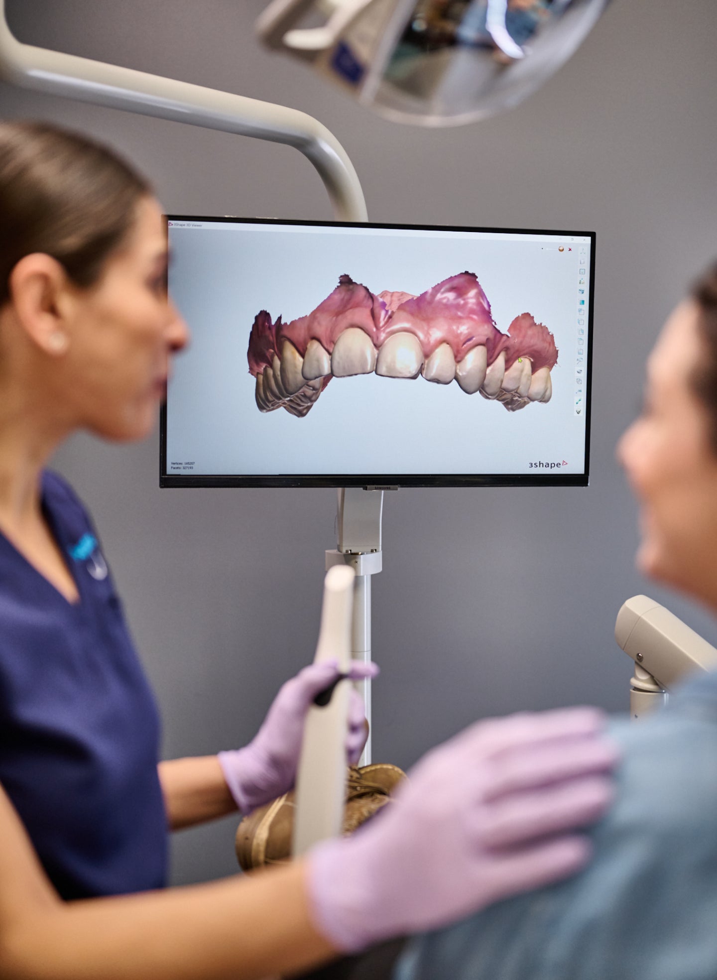 A dentist is showing a picture of a patient 's teeth on a monitor