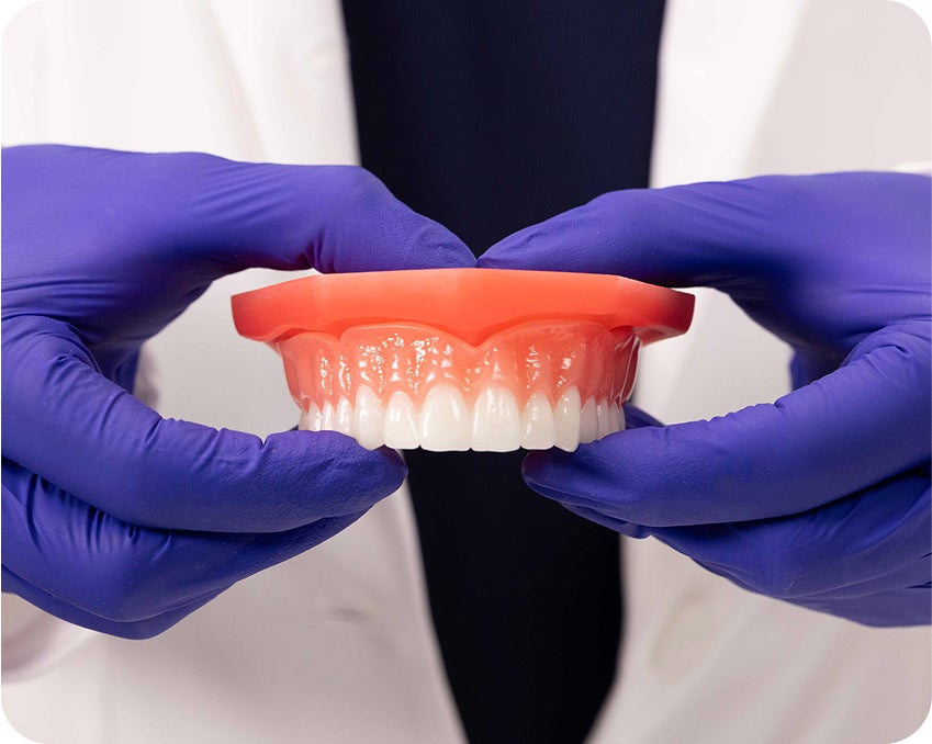 Positioning and pressing an upper denture into place after applying adhesive – Aspen Dental denture placement tip.