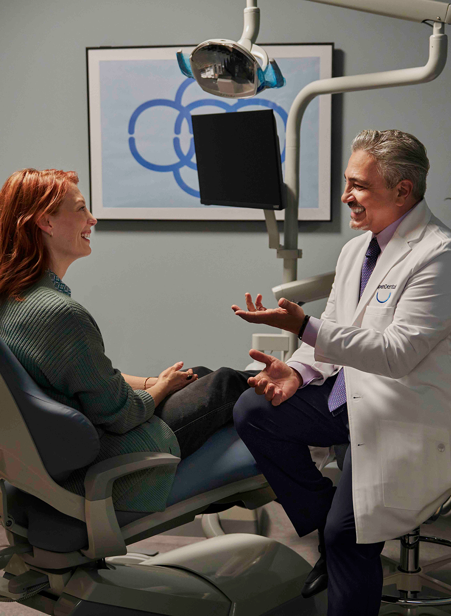 Dentist at Aspen Dental explaining tooth extraction procedure to a patient seated in a dental chair.