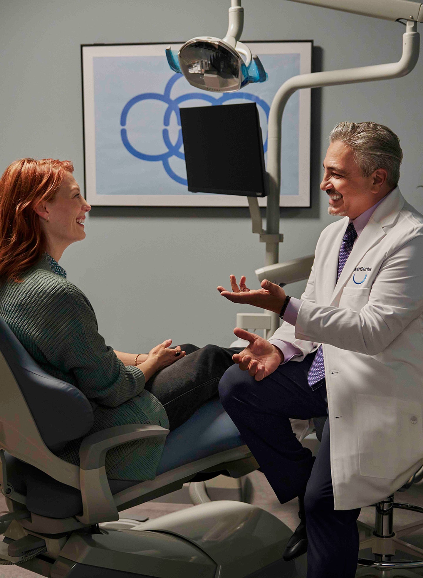 Dentist at Aspen Dental explaining tooth extraction procedure to a patient seated in a dental chair.