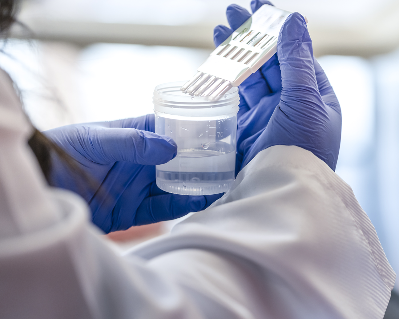 A close up shot of a lab technician's gloved hands as they test a sample.