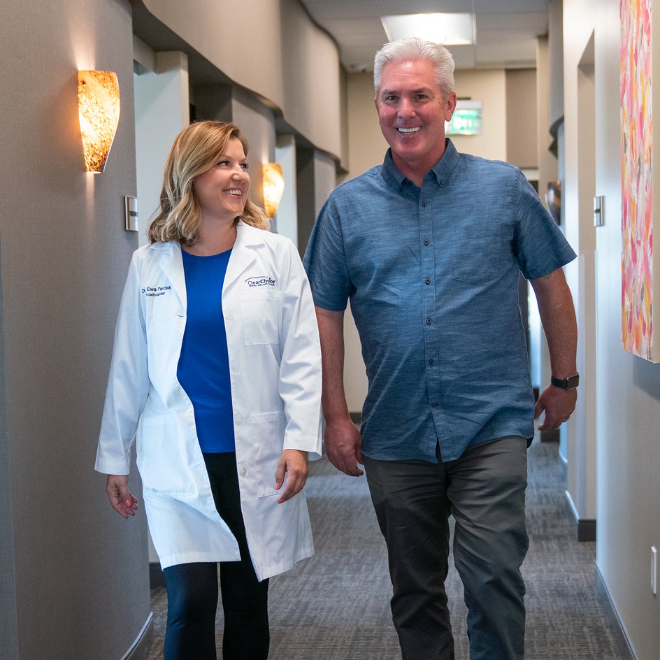 A ClearChoice dental professional walking alongside a patient in a hallway, illustrating the supportive patient journey and personalized financing options available at ClearChoice.