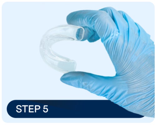 A gloved hand holding a mouthguard, emphasizing the importance of wearing a guard to protect composite veneers from physical stress, chips, and cracks.