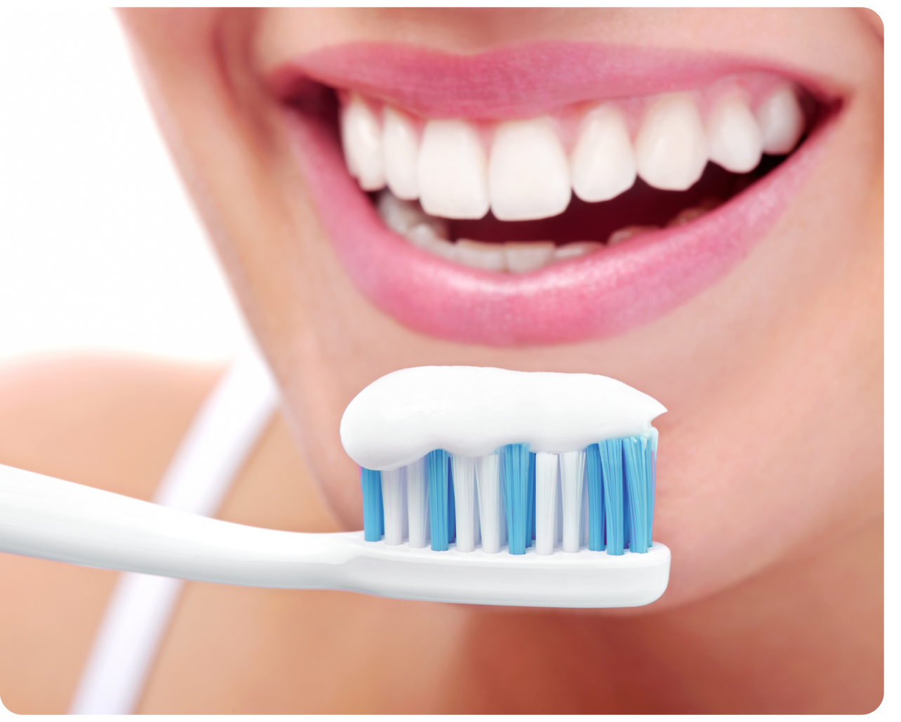 Close-up of a bright smile with a toothbrush coated in toothpaste, promoting good oral hygiene as recommended by Aspen Dental.