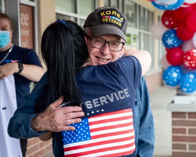 A heartwarming moment of a patient hugging an Aspen Dental team member while holding a patriotic-themed gift during the Healthy Mouth Movement.