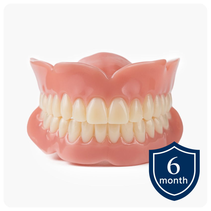 A pair of Aspen Dental Basic dentures displayed on a white background with a 6-month warranty badge in the corner, highlighting affordable denture options with limited warranty coverage.