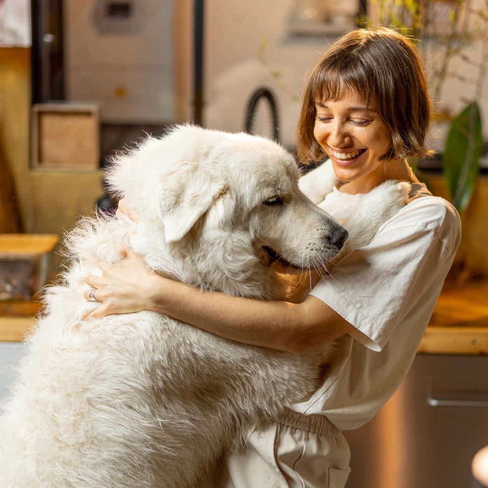 Woman smiling and hugging a large white dog.