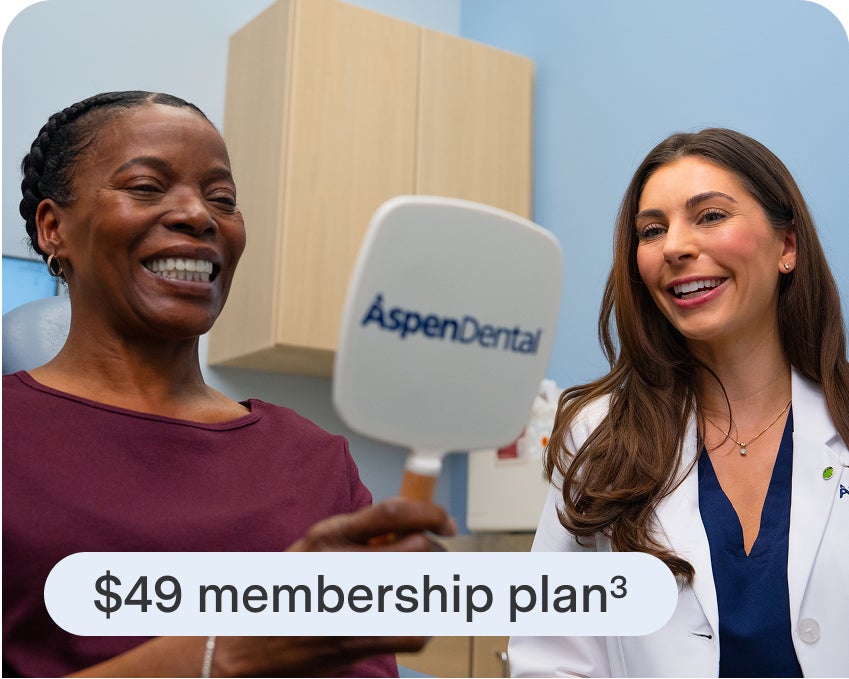 A smiling woman holds an Aspen Dental mirror while a provider stands beside her, with text overlay promoting a $49 membership plan for dentures.