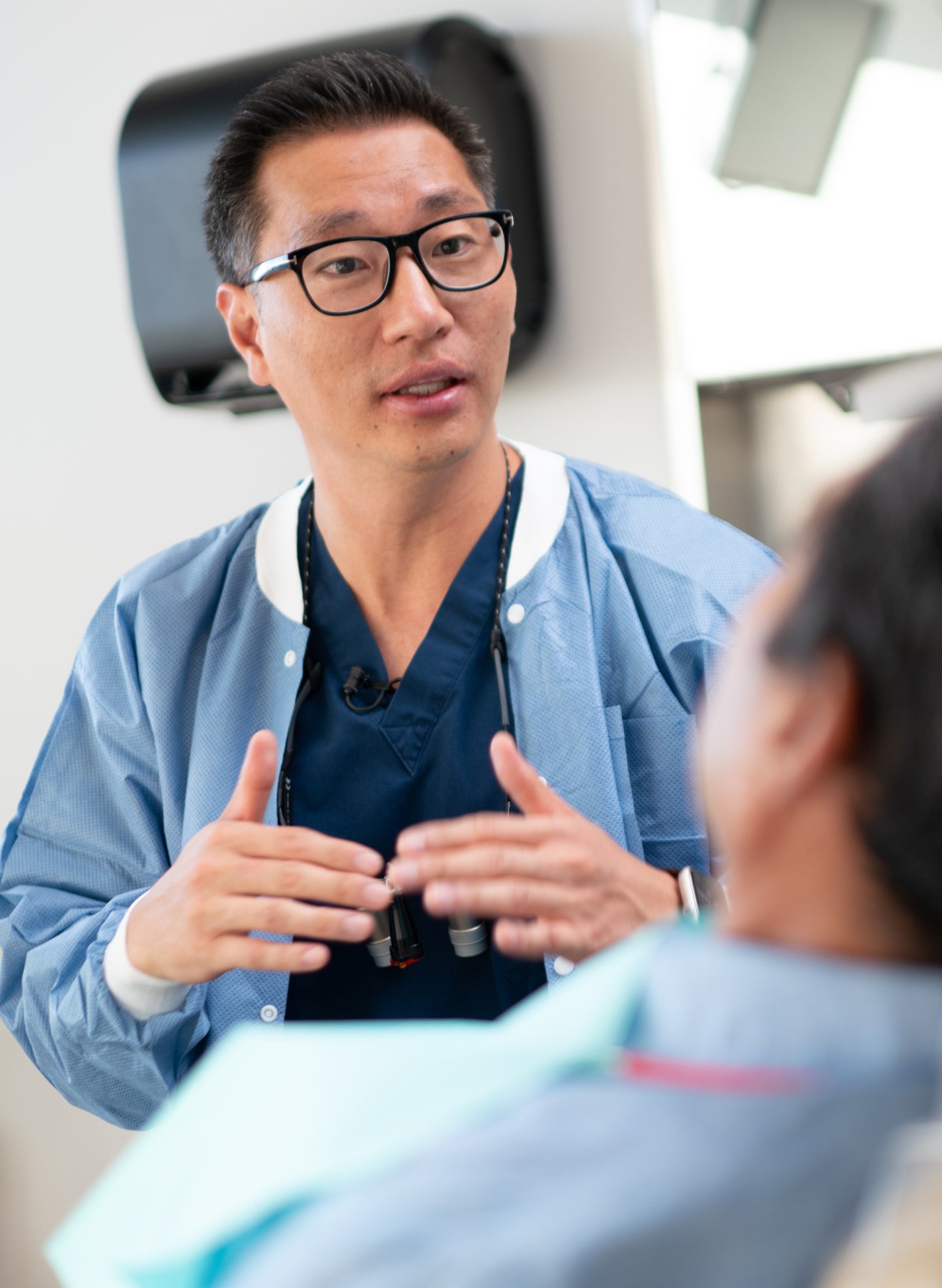 A ClearChoice dental professional in a blue jacket discussing treatment options with a patient, highlighting care for dental implant infections.