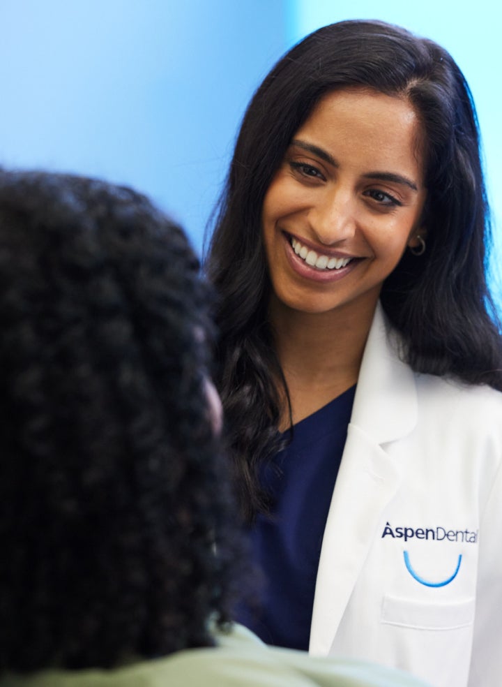 Aspen Dental professional smiling while discussing failed dental implant removal options with a patient in a supportive and caring environment.