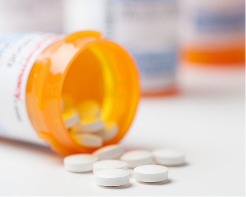 Medication bottle on its side with some pills spilling out.
