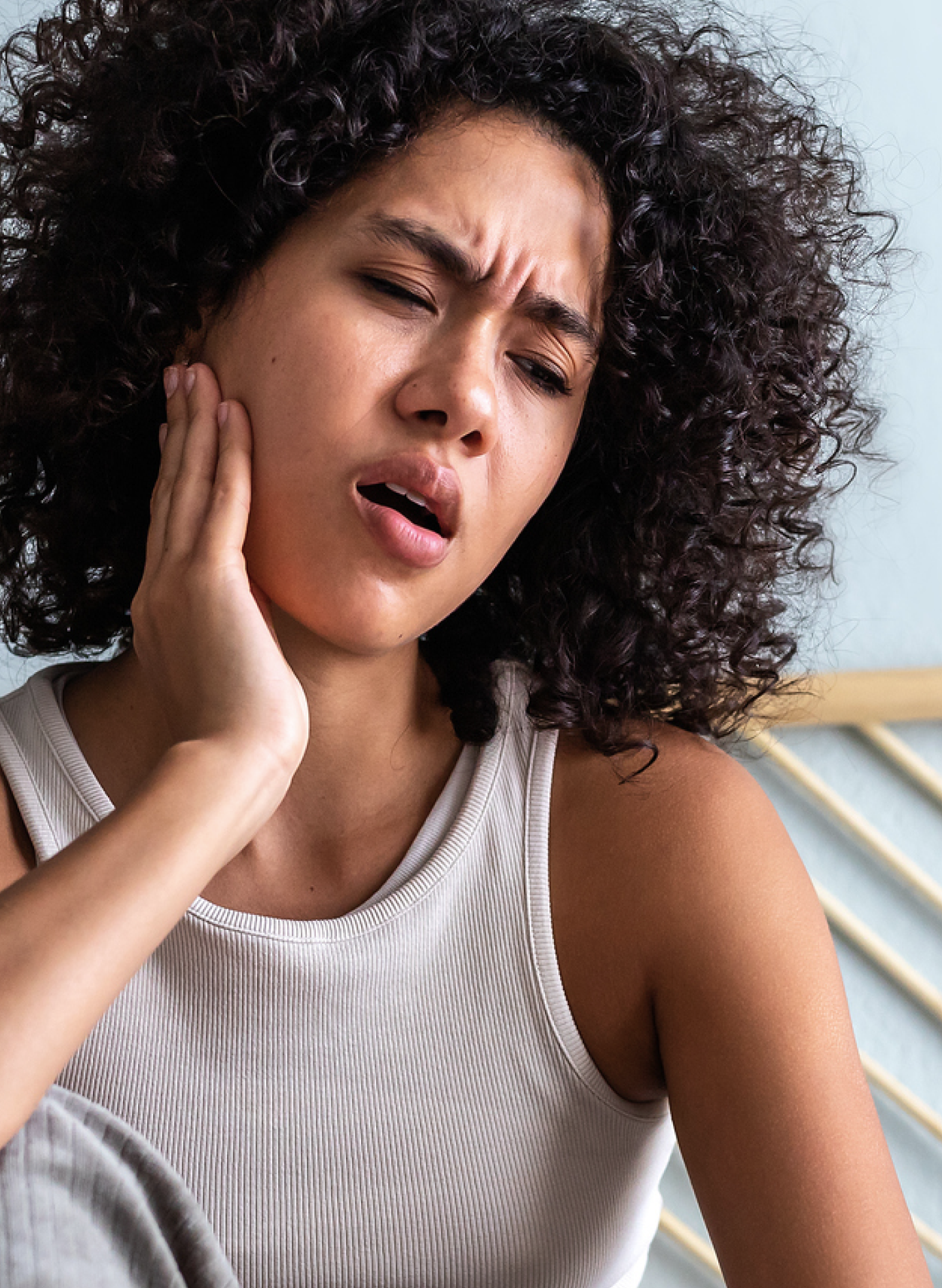 Woman holding her jaw in pain, indicating a toothache or dental discomfort, showcasing Aspen Dental’s focus on providing relief for common oral health issues.