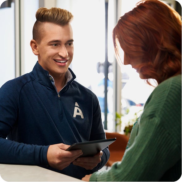 A man in a blue jacket with the Aspen A Logo on it is talking to a woman