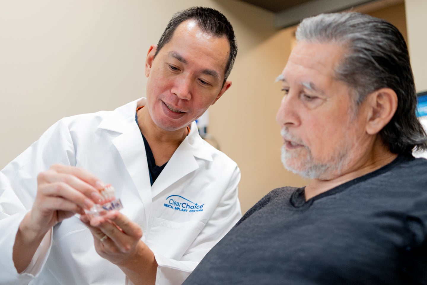 ClearChoice dentist explaining front tooth dental implant options and costs to a patient during a consultation.