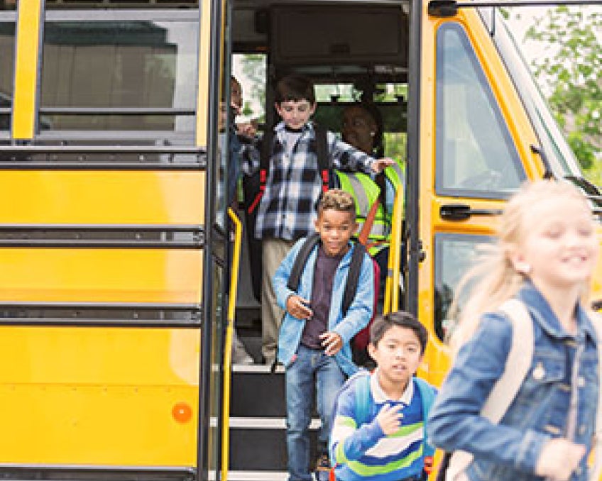 A group of children getting off a yellow school bus