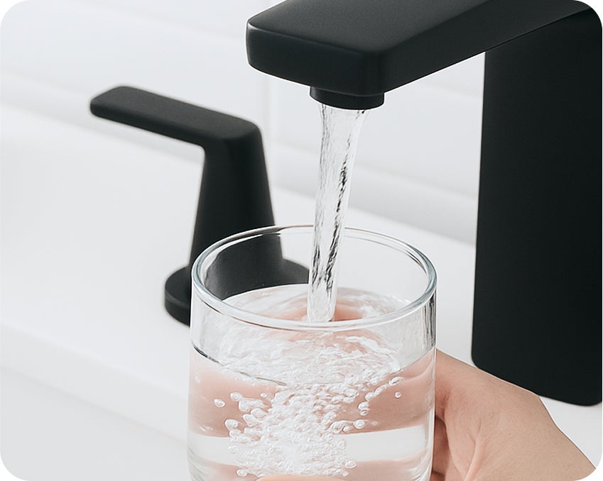 Filling a glass with water at the sink before removing dentures – Aspen Dental oral care routine.