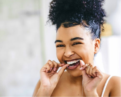 A cheerful individual flossing their teeth, emphasizing the importance of maintaining dental health with Aspen Dental tips.