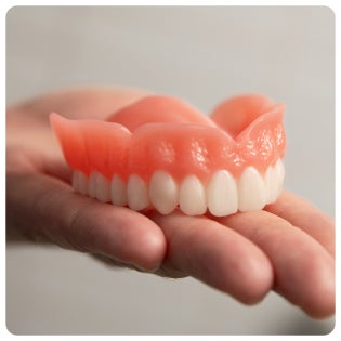 A person is holding a full denture in their hand