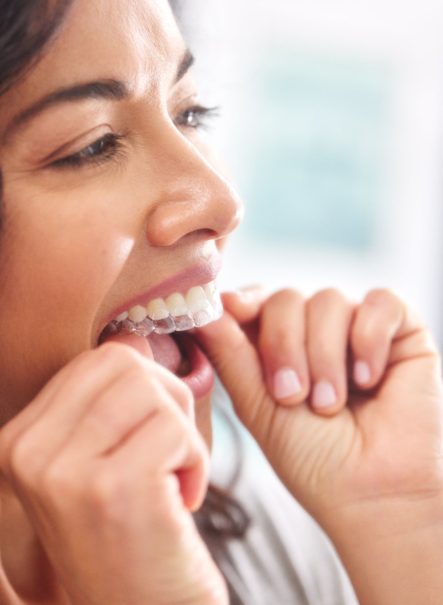 Woman putting in her clear aligners, showcasing the comfort and convenience of Motto Clear Aligners.