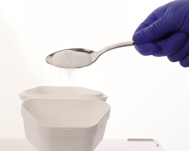 A hand pouring denture cleaning solution into a container to soak dentures. Aspen Dental advises using a room-temperature solution for effective denture care.