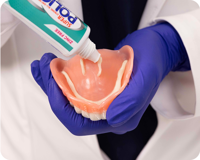 Applying denture adhesive paste in short strips onto an upper denture – Aspen Dental how-to guide.