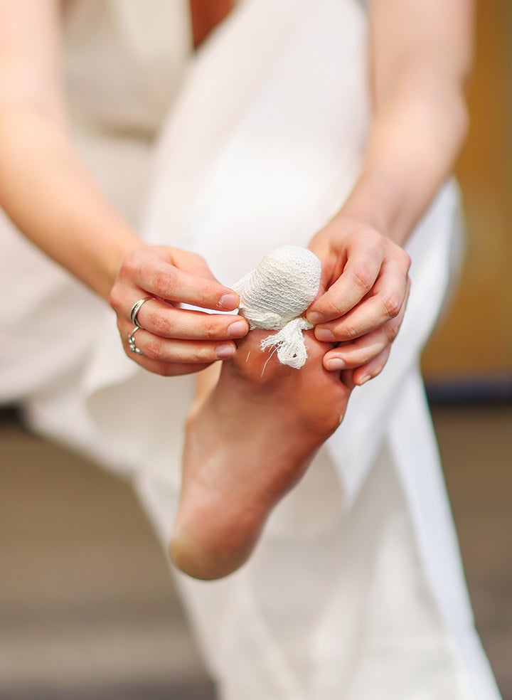 A woman in a white dress is checking the bandage on her toe