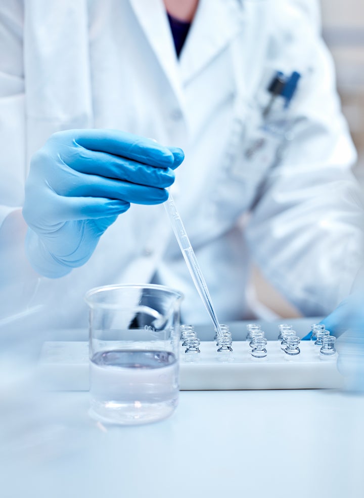 A scientist is using a pipette to pour liquid into a glass