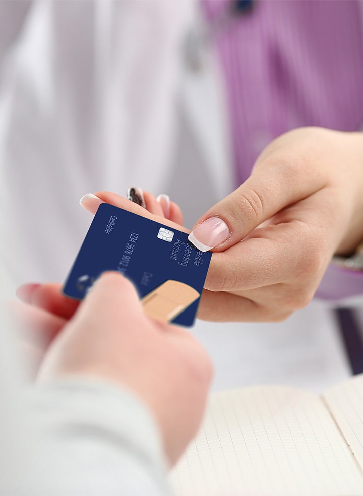 A medical provider holding an insurance card and smiling at a patient.