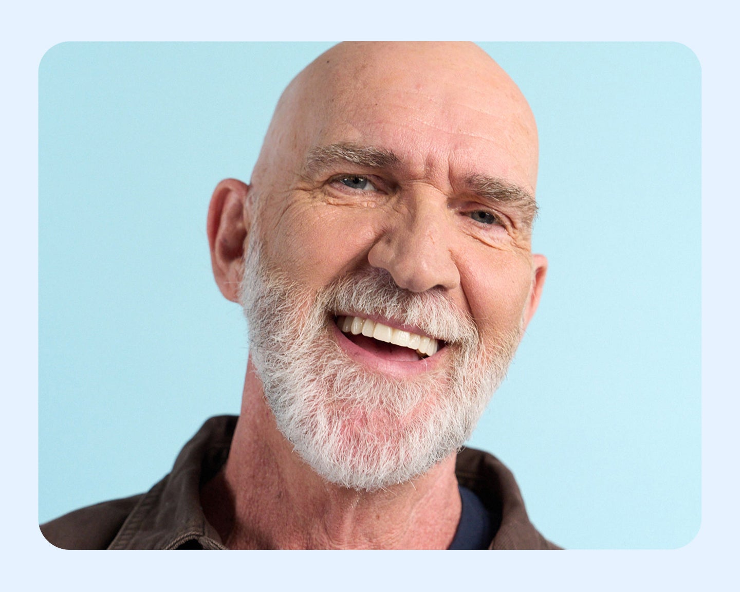 A happy Aspen Dental patient smiles confidently, showcasing the results of a tooth replacement solution. The image highlights the benefits of restoring a natural-looking and healthy smile.