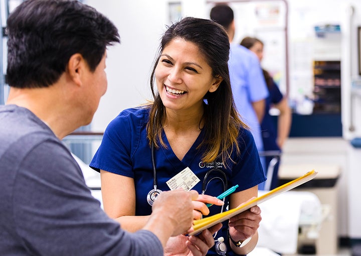 A medical provider smiles at their patient and hands them paperwork to fill out.