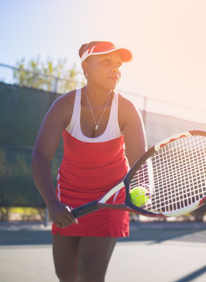A woman is holding a tennis racket and ball on a tennis court