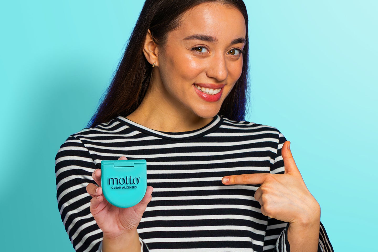 A woman in a striped shirt is pointing at a Motto Clear Aligners container