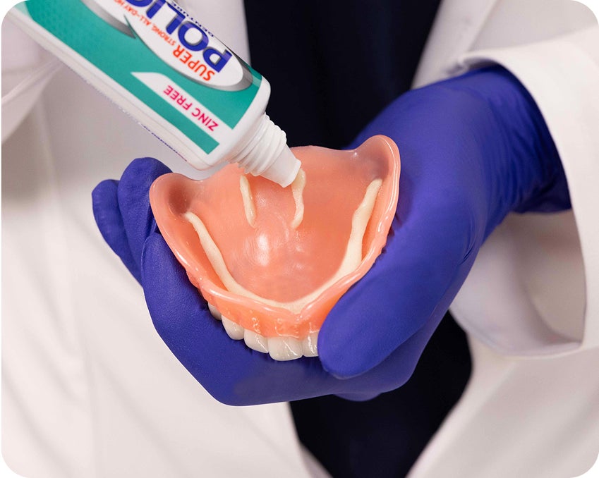 Applying denture adhesive paste in short strips onto an upper denture – Aspen Dental how-to guide.