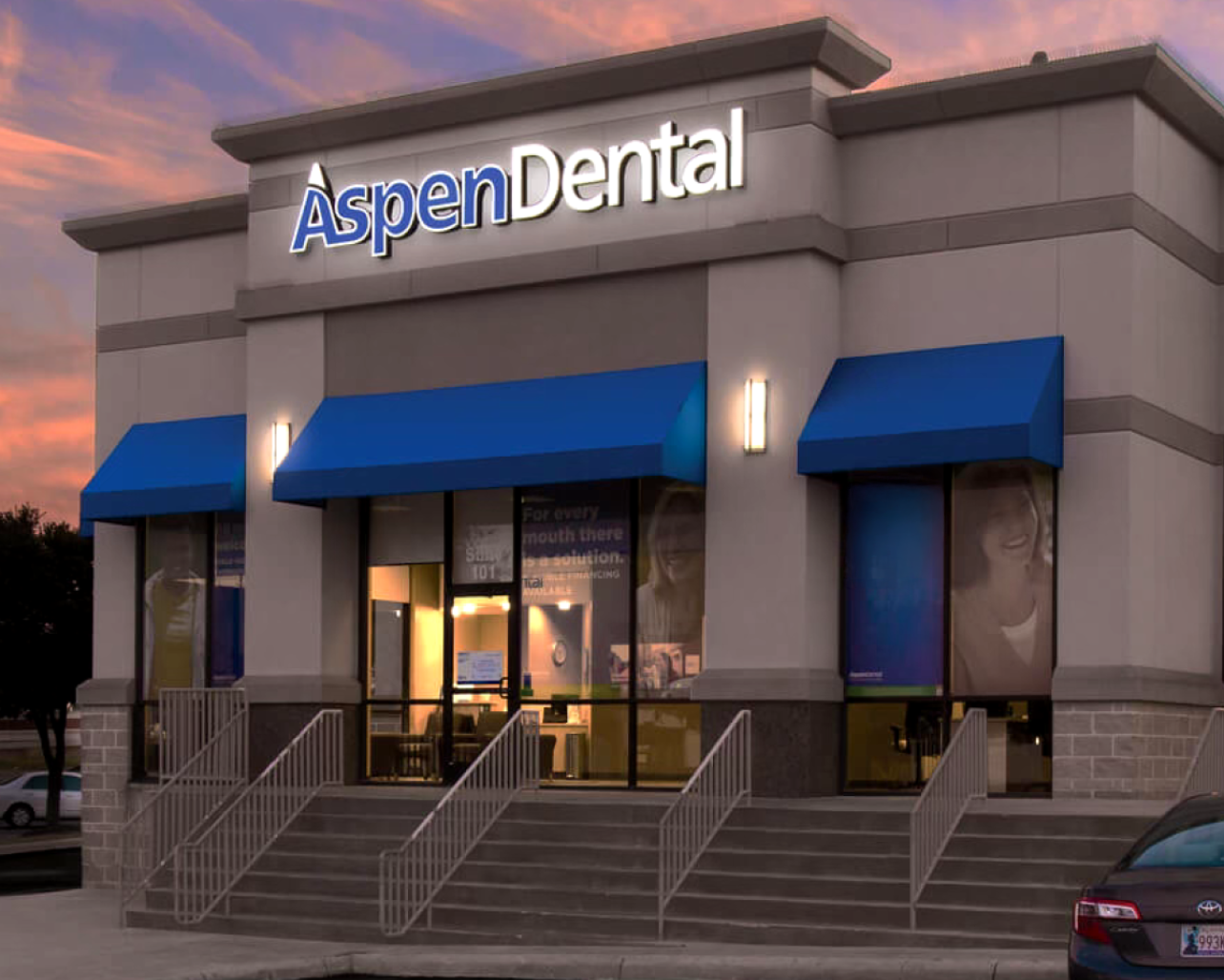 View of an Aspen Dental office building against a bright colored sky at sunset