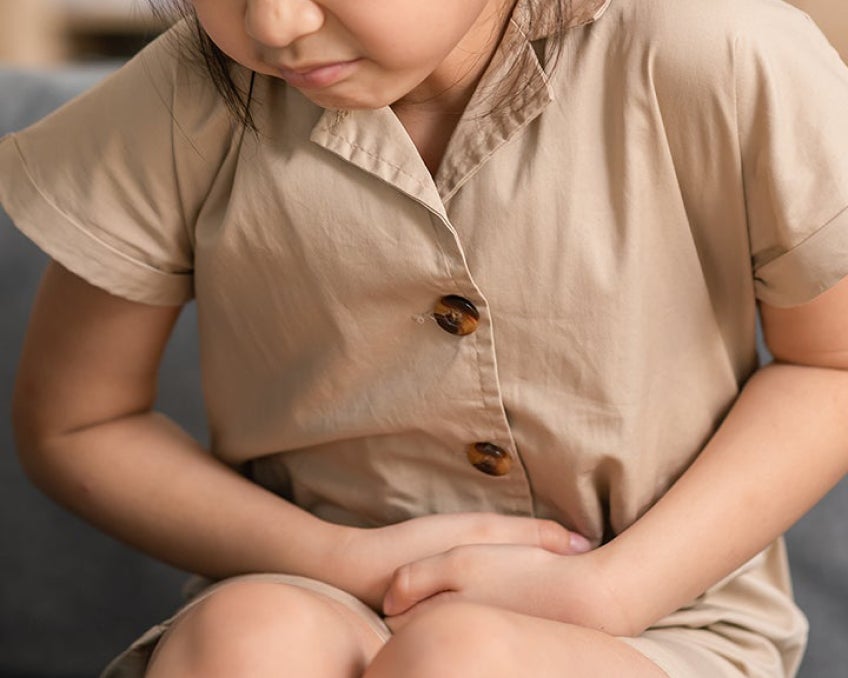A child pressing on their abdomen, experiencing discomfort