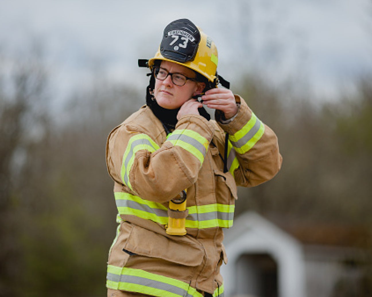 A firefighter putting on their helmet