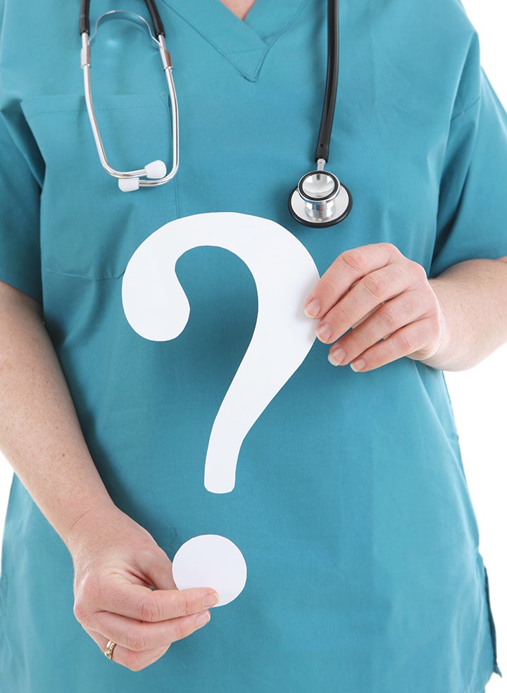 A doctor is holding a white question mark in their hands