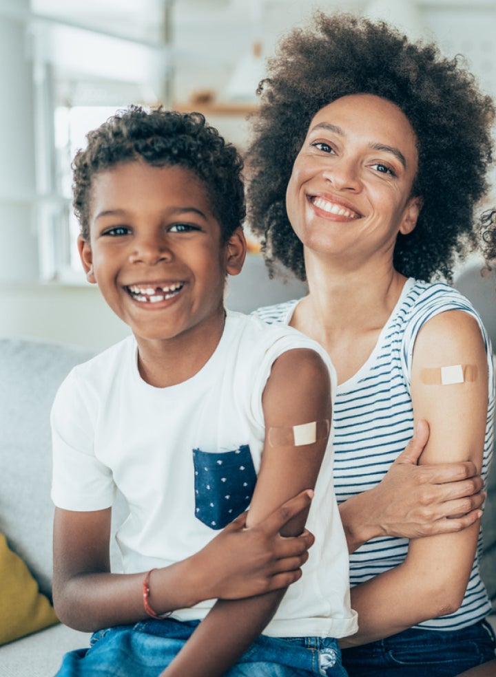 A woman and a boy are sitting on a couch after getting flu shots. 